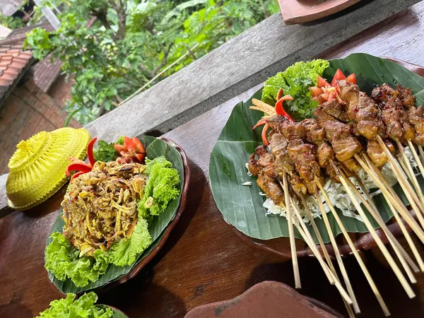 Repas balinais avec satés et plat épicé servis sur feuilles de bananier